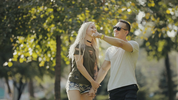 Glückliches junges Paar geht Hand in Hand durch den Stadtpark - Filmmaterial, Video