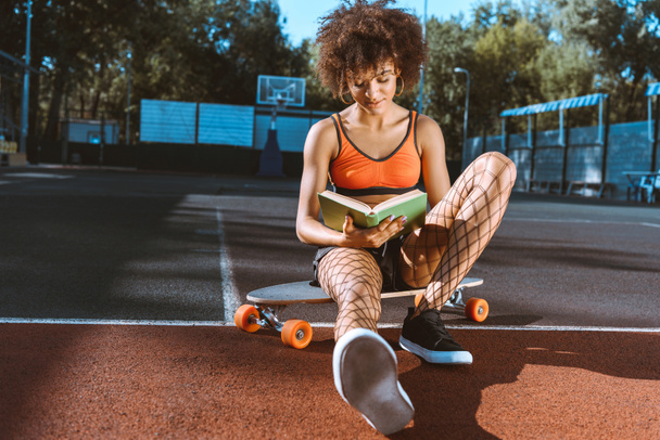 mujer afroamericana en libro de lectura longboard
 - Foto, Imagen