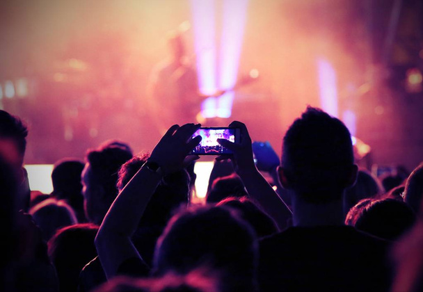 fan toma una foto guitarrista en el escenario durante un concierto en vivo
 - Foto, imagen