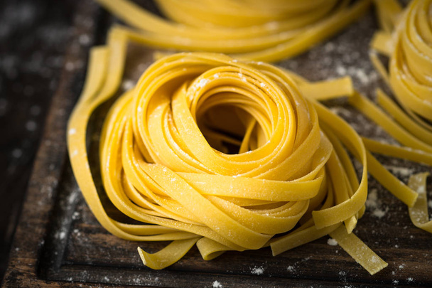Fresh homemade pasta tagliatelle at wooden table. - Фото, изображение