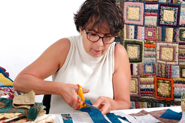 mature brunette woman cutting fabric for sewing patchwork - Photo, Image