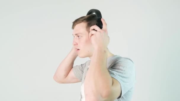Νεαρός βάζει τα ακουστικά του και να ακούτε μουσική σε λευκό φόντο - Πλάνα, βίντεο