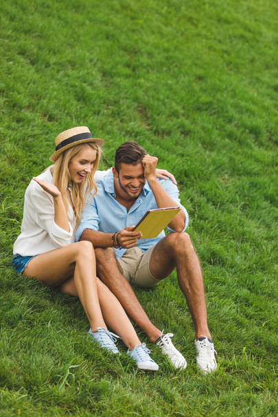 couple with tablet on green lawn - Φωτογραφία, εικόνα