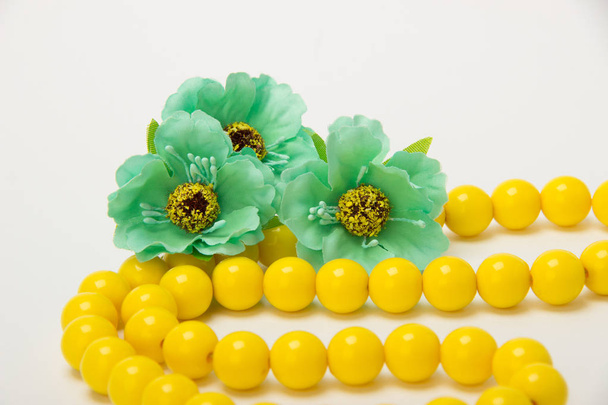 Necklace of yellow beads with green flowers on a white backgroun - Photo, Image