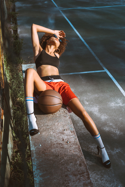 woman in sportswear and heels on bench - Photo, Image
