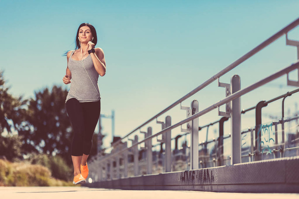City workout. Beautiful woman running in an urban setting - Foto, Imagen