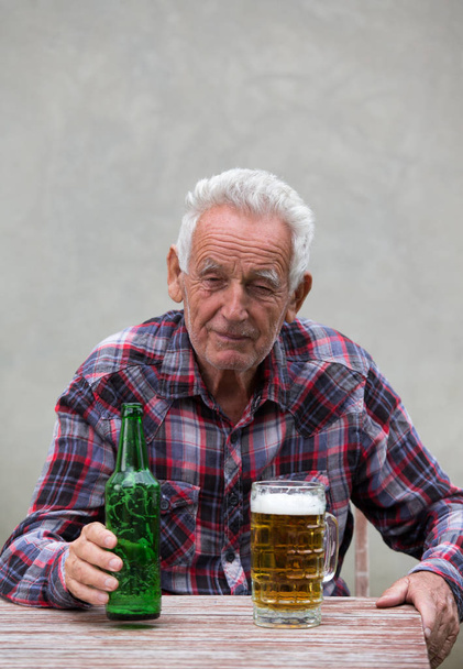 Senior man met bierfles en mok - Foto, afbeelding