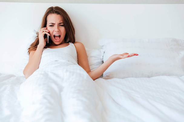 Mad crazy woman lying in empty bed and screaming - Photo, Image