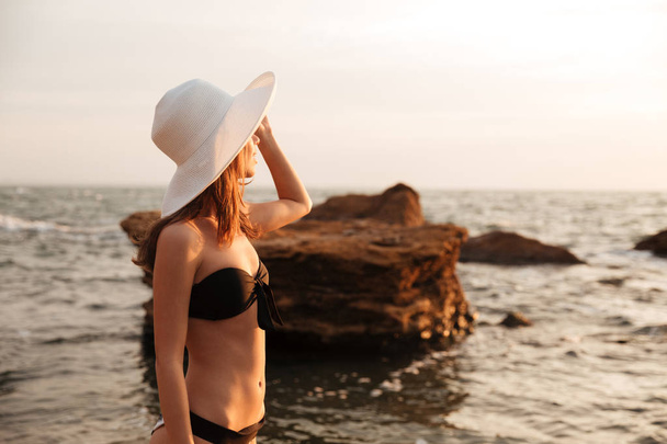 Side view of brunette woman in hat and bikini - Valokuva, kuva