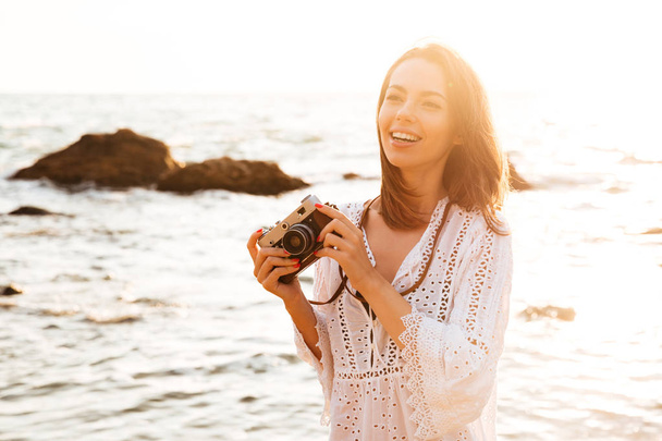 Laughing brunette woman in light summer dress posing on beach - Fotoğraf, Görsel