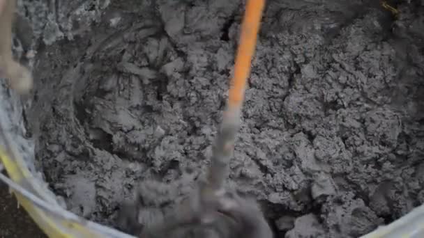Man mixes glue with concrete drill. Man mixing concrete glue with special long drill attached to drilling machine, Spinning hand mixer mixing cement mortar for plaster walls - Footage, Video