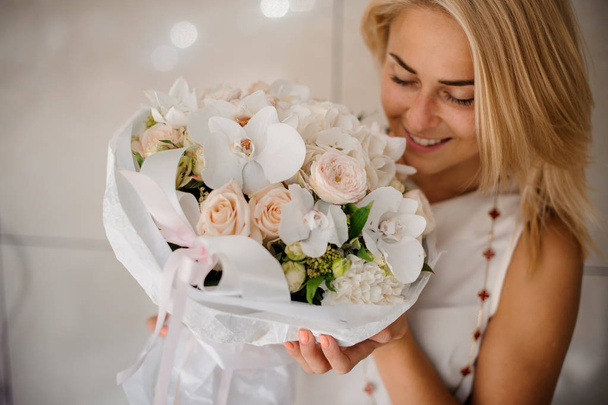 Smiling young woman holding a composition of flowers - Foto, Bild