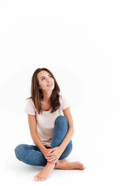 Vertical image of happy brunette woman sitting on the floor - Photo, Image