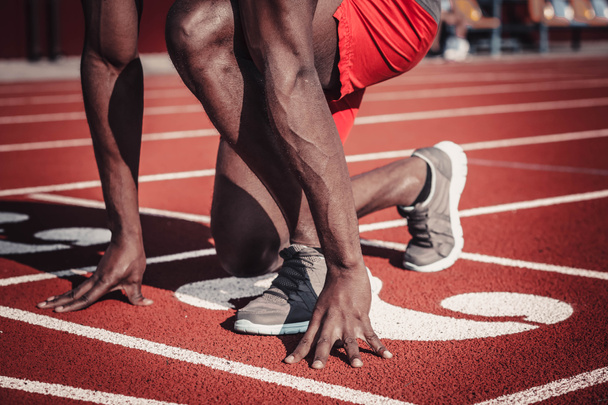 Hands and feet of a dark-skinned man on the track of the stadium - Photo, Image