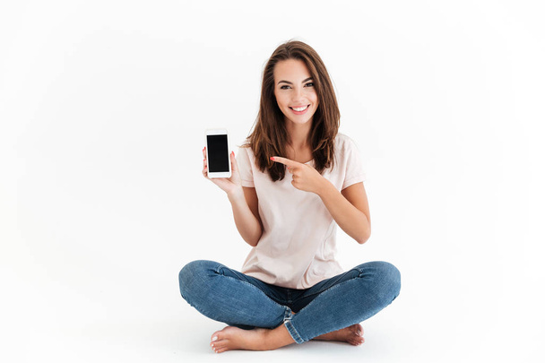 Smiling brunette woman showing blank smartphone screen - Foto, Imagen