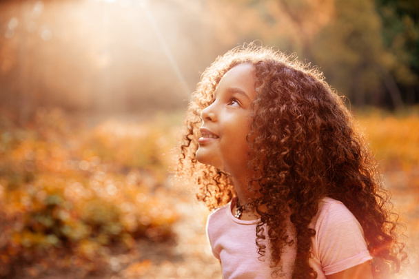 Afro americana linda niña con pelo rizado recibe milagrosos rayos de sol del cielo
 - Foto, Imagen