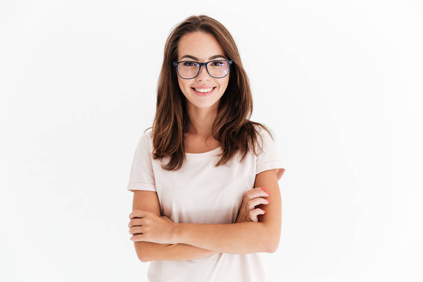 Smiling brunette woman in eyeglasses posing with crossed arms - Фото, изображение