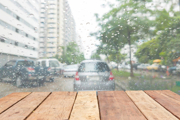 перспектива дерев'яна дошка порожній стіл перед розмитим дощем на лобовому склі автомобіля на вулиці
 - Фото, зображення