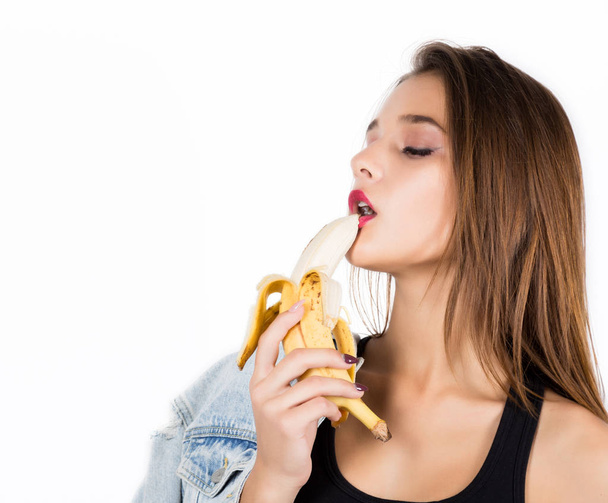 Young sensual woman eating banana on white background. provocation concept - Fotografie, Obrázek