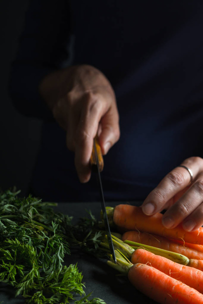 Crop is cut off from the carrot with a knife - Fotoğraf, Görsel
