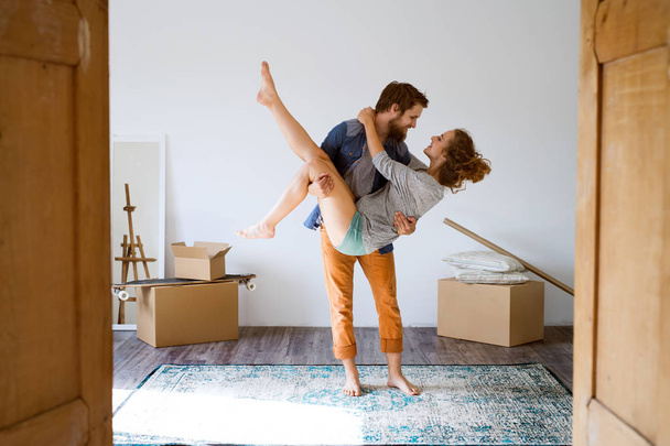 Man carrying woman in his arms, moving in new house. - Fotoğraf, Görsel