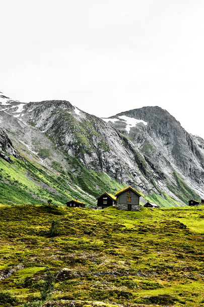 Χόρτο στην οροφή σπίτια στα βουνά της Νορβηγίας με καταπράσινα λιβάδια και ένα ποτάμι λευκό νερό στο προσκήνιο - Φωτογραφία, εικόνα