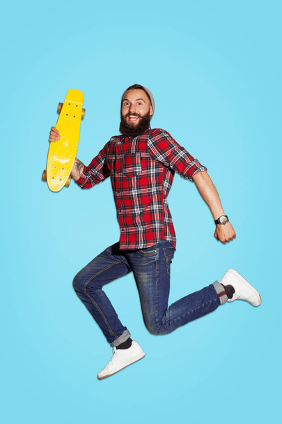 Excited man jumping with skate in studio - Zdjęcie, obraz