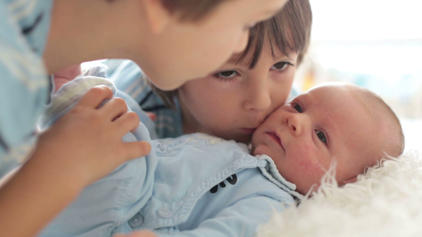 Hermoso niño, abrazándose con ternura y cuidando a su hermano recién nacido en casa. Familia amor felicidad concepto - Imágenes, Vídeo