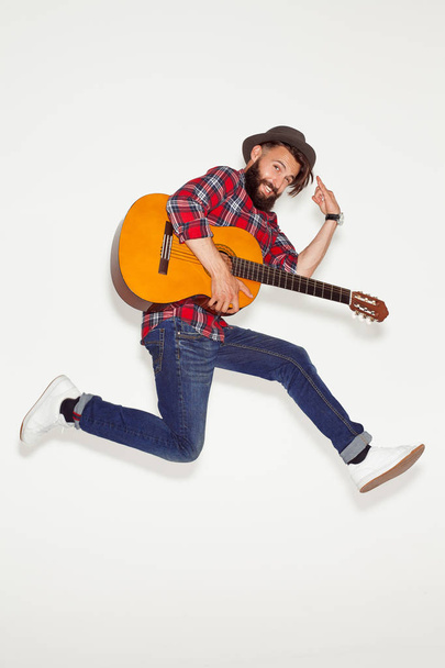 Dynamic man posing with guitar on white - Фото, изображение