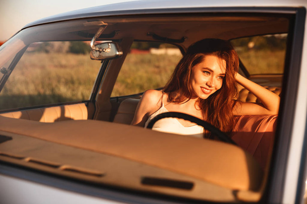 Smiling brunette woman sitting inside car - 写真・画像