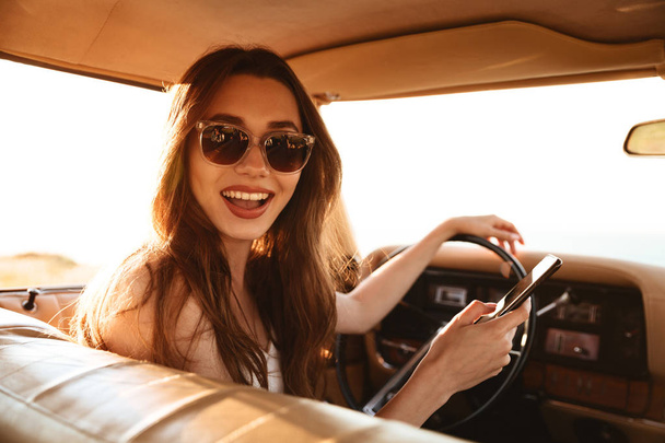 Picture from car of happy brunette woman in singlasses - Photo, image