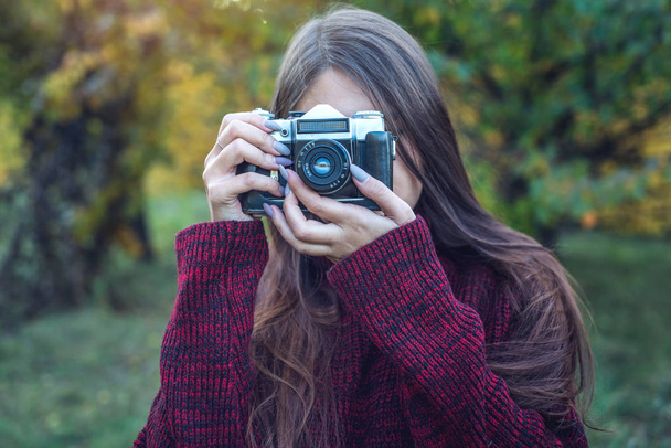 Bella donna in autunno Park tiene vintage fotocamera retrò. Concetto di fotografia come hobby
 - Foto, immagini