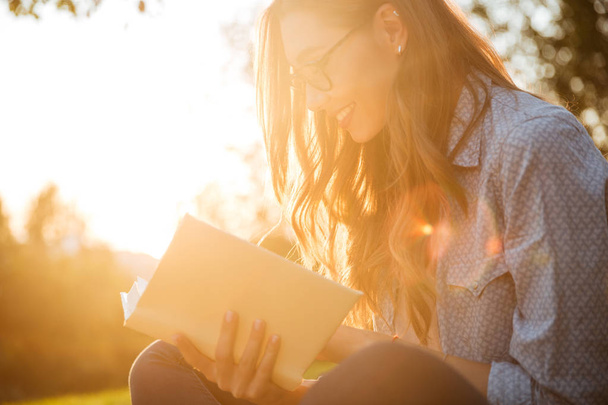 Cropped image of happy brunette woman in eyeglasses reading book - Zdjęcie, obraz
