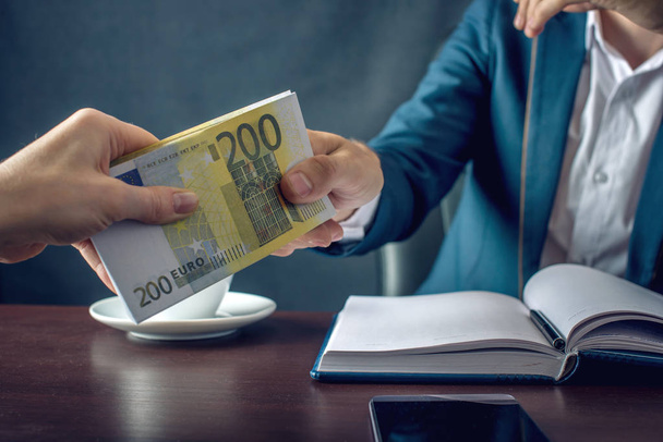 Podnikatel muž v obleku bere do rukou peníze. Úplatek v podobě bankovek eura. Pojem korupce a úplatkářství - Fotografie, Obrázek