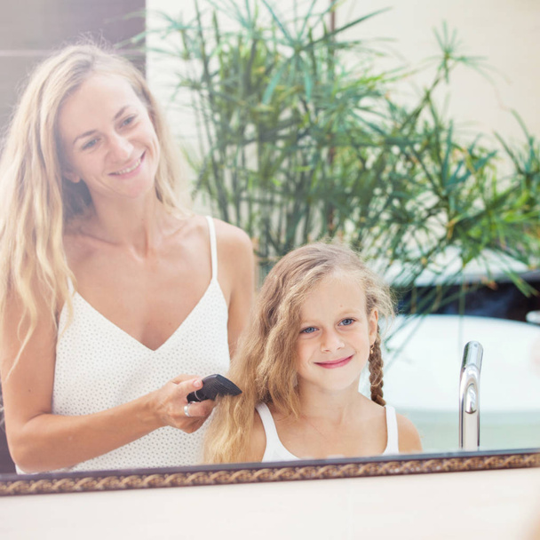 Mother combing daughter hair - Foto, afbeelding