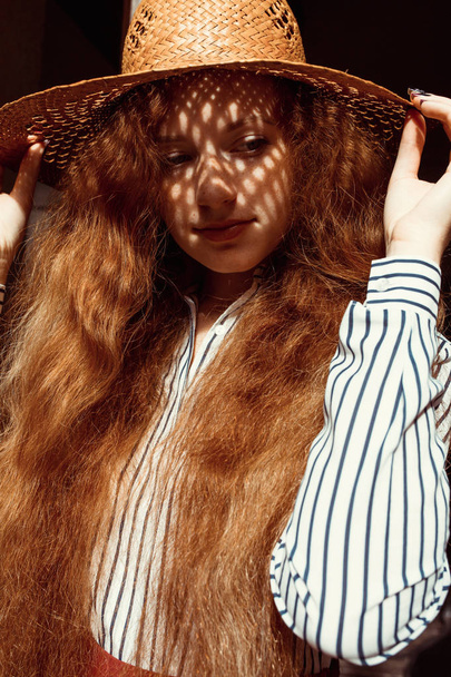 Elegant young red haired model in straw hat with shadow on her f - Foto, imagen