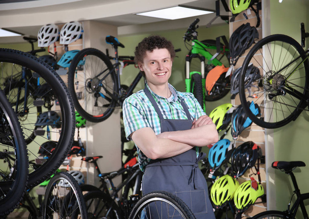Young man standing in bicycle shop - 写真・画像
