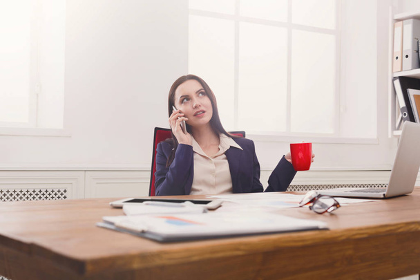 Ділова розмова, жінка консультує по телефону в офісі
 - Фото, зображення