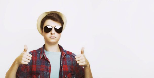 Pohledný muž objevil palce s sluneční brýle a klobouk ve studiu - Fotografie, Obrázek