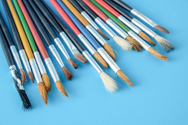 Row of artist paint brushes close up on blue  background - Foto, imagen