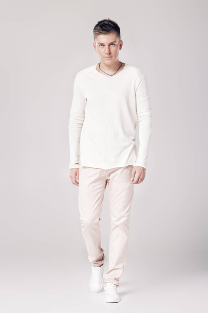 handsome young man in a white sweater and pants - Photo, image