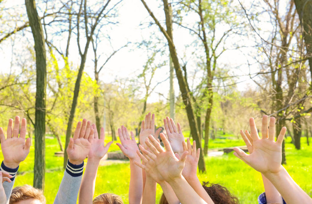 Young people putting hands in air together outdoors. Volunteering concept - Photo, Image