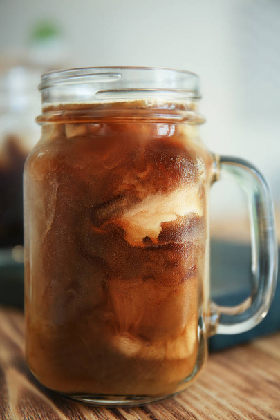 Mason jar met cold brew koffie en melk op houten tafel - Foto, afbeelding
