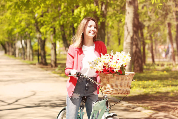 若い女の子と自転車と花のバスケット - 写真・画像