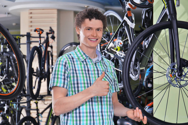 Young man choosing bicycle in shop - Фото, изображение