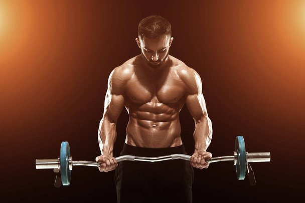 Uomo muscolare sollevamento pesi su sfondo scuro
 - Foto, immagini