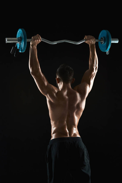 bodybuilder lifting a barbell on black background - Фото, зображення