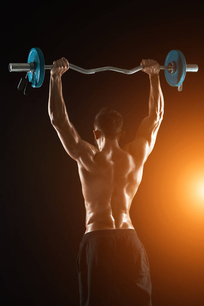 bodybuilder lifting a barbell on black background - Fotografie, Obrázek