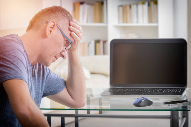 Freelancer man at workplace in office holding his head on hands - Photo, Image