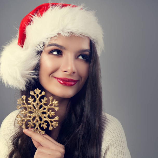 Beautiful Christmas Woman in Santa Hat Holding Golden Snowflake  - Fotografie, Obrázek
